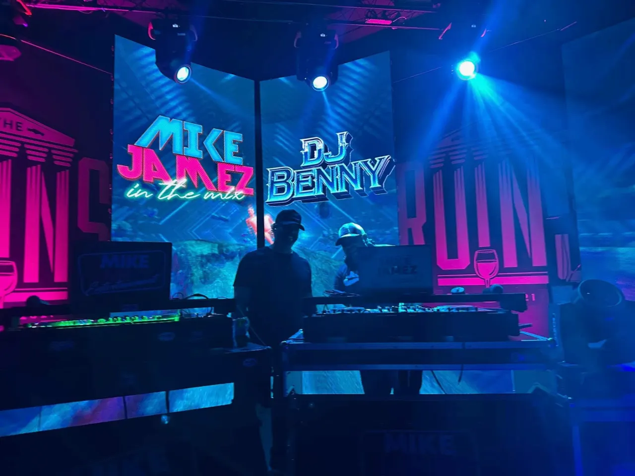 Two DJs performing in front of a split LED wall displaying event graphics